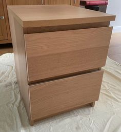 a wooden dresser sitting on top of a white sheet covered floor next to a cabinet