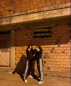 two people standing in front of a brick building