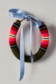 a wreath with a blue ribbon hanging from it's side on a white wall