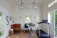 a home gym with treadmills and exercise equipment in the room, along with two windows