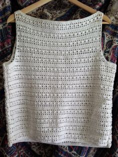 a white crocheted top hanging on a wooden hanger