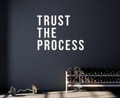 a gym room with dumbs and a wall that says trust the process