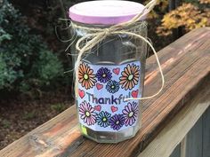 a mason jar with a pink lid sitting on top of a wooden fence