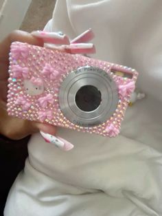 a person holding a camera in their hand with pink and white decorations on the cover