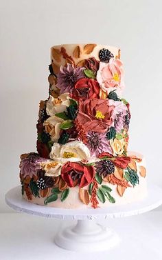 a three tiered cake decorated with flowers and leaves