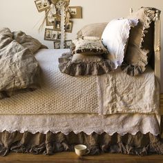 a bed with ruffled bedspread, pillows and pictures on the wall behind it