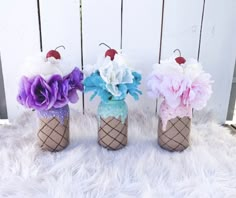 three vases with flowers in them sitting on a fur rug