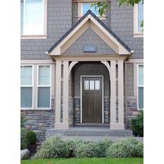 the front entrance to a house with stone and wood trimmings on the side