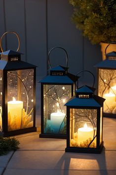 three lit lanterns sitting next to each other on a sidewalk with trees in the background