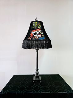 a lamp that is sitting on top of a black table with a white wall in the background