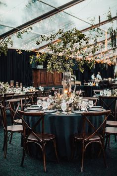 an outdoor tent with tables and chairs set up for dinner