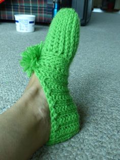 a person's feet with green knitted slippers