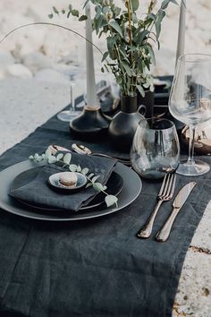 a table set with black plates and silverware