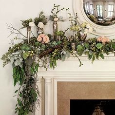 a mantel decorated with greenery and flowers in front of a mirror on the wall