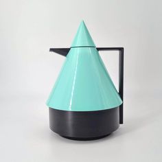 a teal and black vase sitting on top of a white table