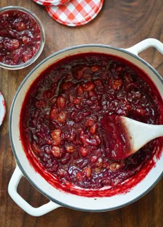 a pot filled with cranberry sauce on top of a wooden table next to other dishes