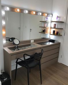 a chair sitting in front of a vanity with lights on it