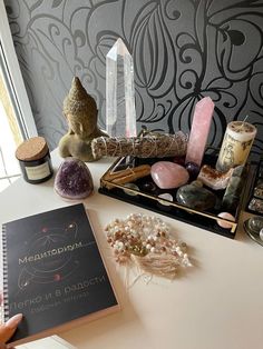 a table topped with lots of different types of rocks and crystals next to a book