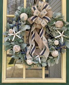 a wreath with seashells and starfish is hanging on the front door window