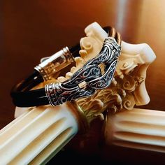 This is a bracelet inspired from Greek Mythology. It features two rows of smooth black leather cords with an engraved sterling silver clasp to hold them in place.  The unique rope knot station in the front is etched with a free flow design in sterling silver with darkened crevices. We can change the length of the bracelets as desired For more Byzantine designs visit : https://www.etsy.com/shop/YianniJewellery Black Symbolic Engraved Bracelets, Symbolic Black Engraved Bracelets, Silver Bracelets With Leather Strap As A Gift, Black Leather Bracelet With Sterling Silver Clasp, Silver Leather Bracelet With Sterling Clasp As Gift, Black Leather Bracelet With Sterling Silver Clasp As Gift, Gift Black Leather Bracelet With Sterling Silver Clasp, Engraved Silver Sterling Leather Bracelet, Engraved Sterling Silver Leather Bracelet