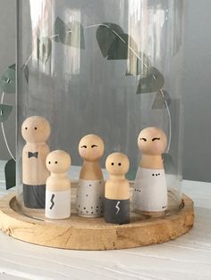 a group of wooden dolls sitting in front of a glass dome with leaves on it