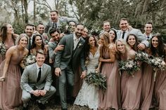 a group of people standing next to each other in front of trees and bushes with flowers on their heads