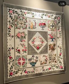 a quilted wall hanging on the side of a wall with flowers and birds in it