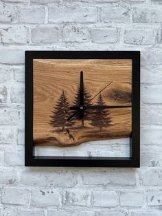 a clock made out of wood with pine trees on it's face and black frame