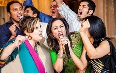 a group of people singing into microphones in front of a man with his arms up