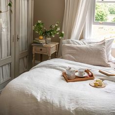 a bed with white linens and pillows in front of a window