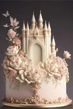 a white cake with pink flowers and a castle on it's side, sitting on a table