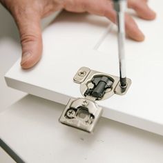 a person is using a screwdriver to fix a piece of furniture that has been painted white