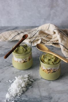 two jars filled with food sitting on top of a table next to a wooden spoon