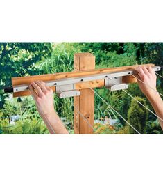 a man is working on a wooden post with two hands and holding it up to the pole