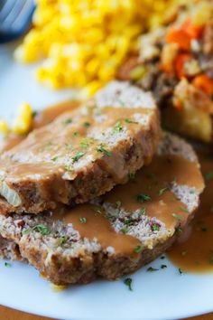 meatloaf with gravy and corn on the cob is served on a plate