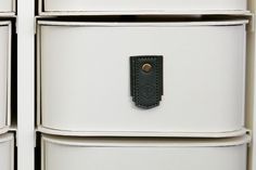 a close up of a drawer with some drawers in front of it and a leather tag on the bottom