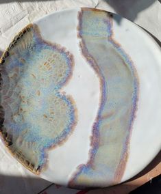 a white plate with blue and purple designs on it, sitting on a table top