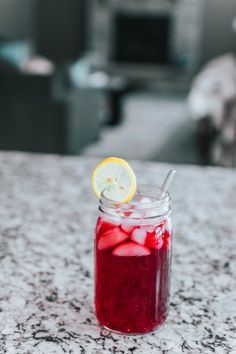 a mason jar filled with liquid sitting on top of a counter next to a lemon slice