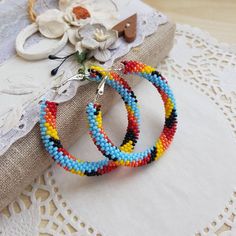 two pairs of multicolored beaded hoop earrings sitting on top of a doily