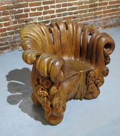 a carved wooden chair sitting on top of a cement floor next to a brick wall with the words, what do you think about this tree stump chair?