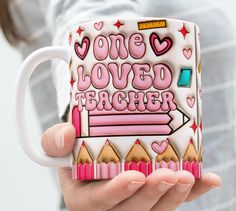 a woman holding a coffee mug with the words love loved teacher on it