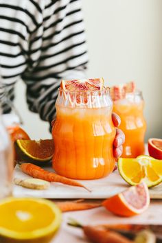 a person holding a pitcher filled with orange juice and garnished with grapefruit