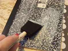 a person is using a brush to paint the fabric on a piece of paper with black and white designs