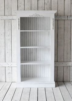 an empty white bookcase against a wooden wall