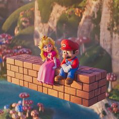 there are two figurines sitting on top of a brick wall and mushroom land