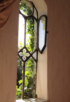 an open window with vines growing on the wall and in between it is a mirror