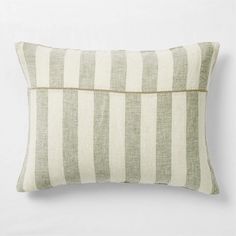 a white and green striped pillow with zippers on the front, sitting against a white wall