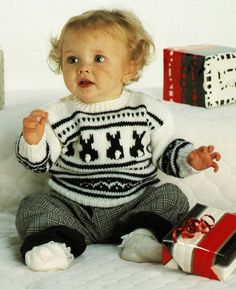 a baby sitting on top of a bed next to presents