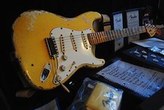 a yellow guitar sitting on top of a table next to papers and other items in front of it