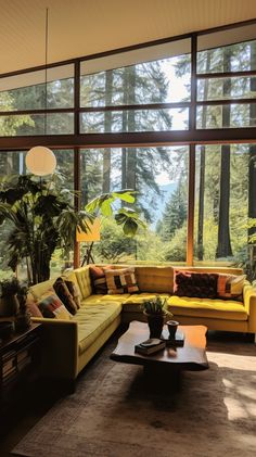 a living room filled with lots of furniture and large windows overlooking the trees in the background